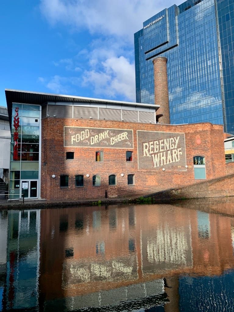 Regency Wharf brick warehouse reflected in the canal near Gas Street Basin, with the Hyatt Regency behind